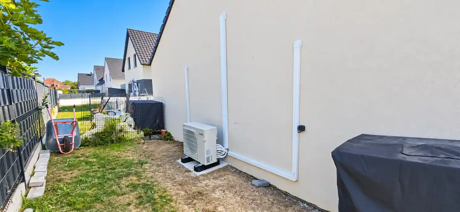 Unité extérieure de climatisation réversible Mitsubishi Electric installée sur une maison Phénix à Oberhergheim par Solest Énergies